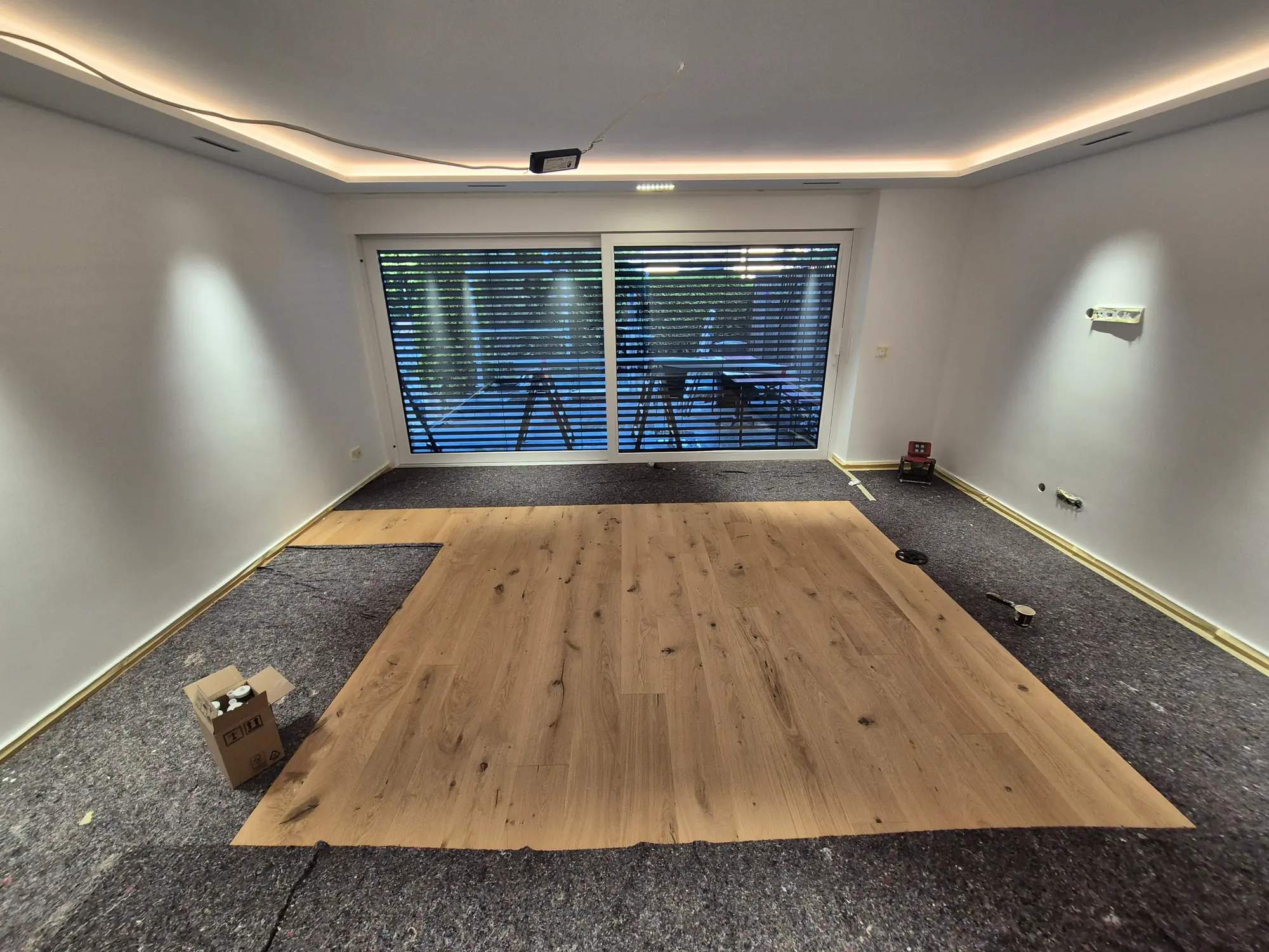 Neu verlegter Holzboden in einem sanierten Wohnzimmer mit Lichtdecke – Bodenverlegung von Mesret Bau