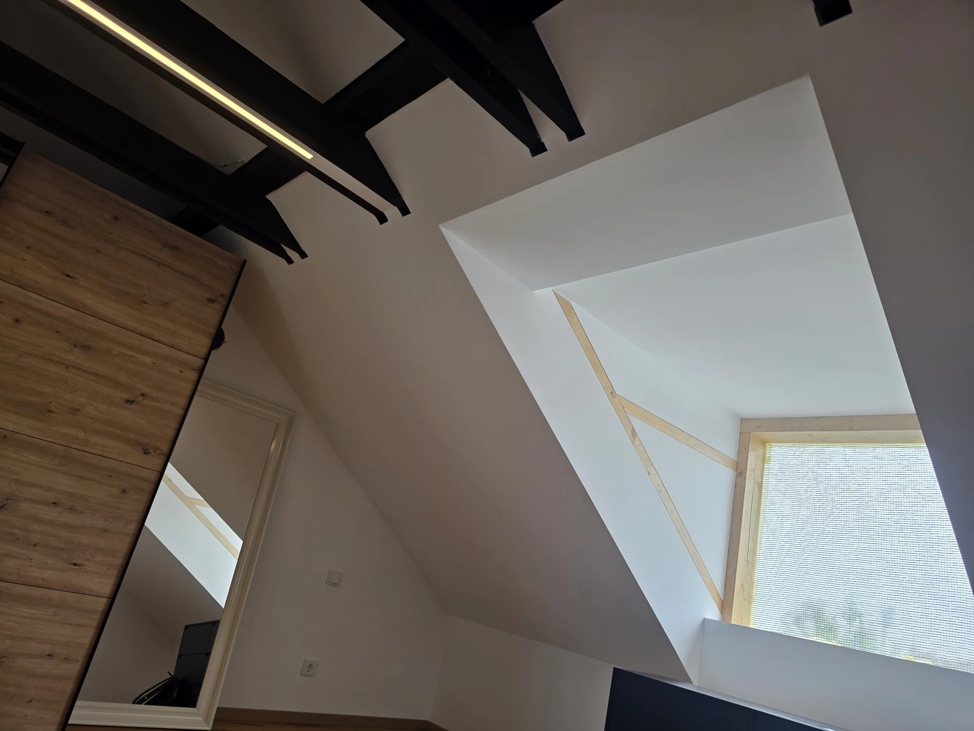 Saniertes Dachgeschoss mit Holzbalken und Dachfenster – Mesret Bau