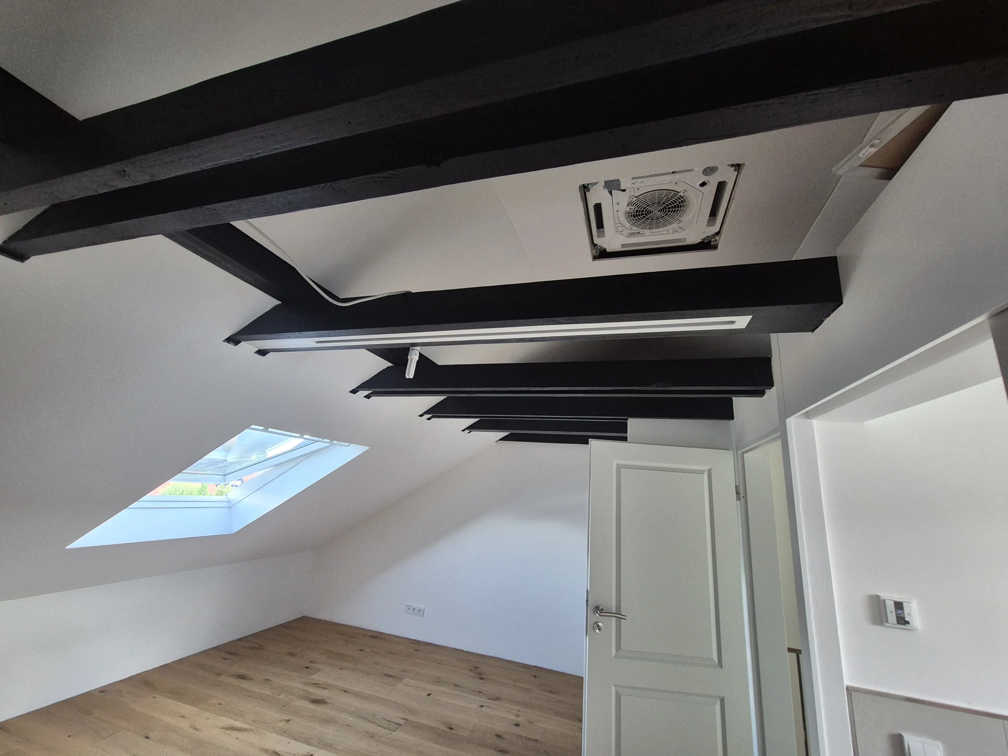 Saniertes Dachgeschoss mit sichtbaren Holzbalken und neuem Boden – Mesret Bau